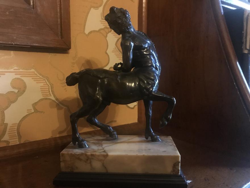 bronze centaur with his head thrown back and arms behind his back standing on a rectangular marble base