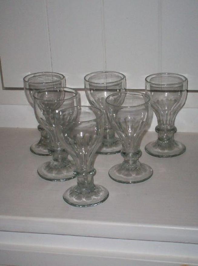 Six clear glass wine glasses with hollow stems.  One ring encircling stem.  Fluting near base of bowl.
