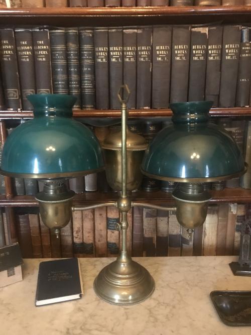 This American brass student lamp, originally oil and now electric, has green glass, lined globes, which are reproductions