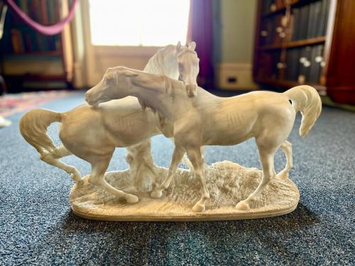 white carved marble pair of horses standing on a single attached marble oval base