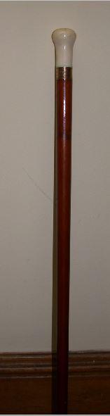 Man's walking stick. Tapering mahogany shaft with a bulbous ivory head. Brass sleeve at tip. The ivory knob has a small hole drilled in the top. The knob is cracked on the sides and has two smaller cracks in the top. A brass or gold band under the knob is engraved "Carved from the hand Railing of the Old Dept. of State/Wm. H. Seward.
