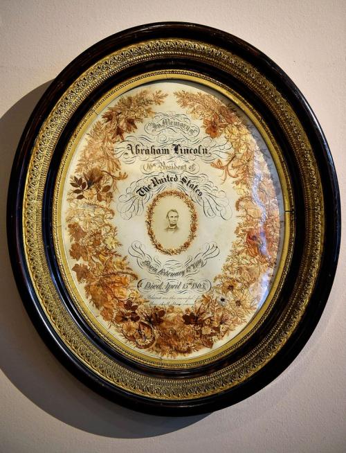 Oval engraving announcing the death of President Abraham Lincoln. Decorated with pressed flowers from the President's casket.